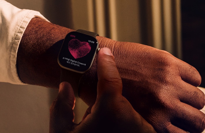 Apple Watch Series 11의 Digital Crown을 길게 눌러 심전도 앱에서 심장 건강을 측정하는 사람의 모습