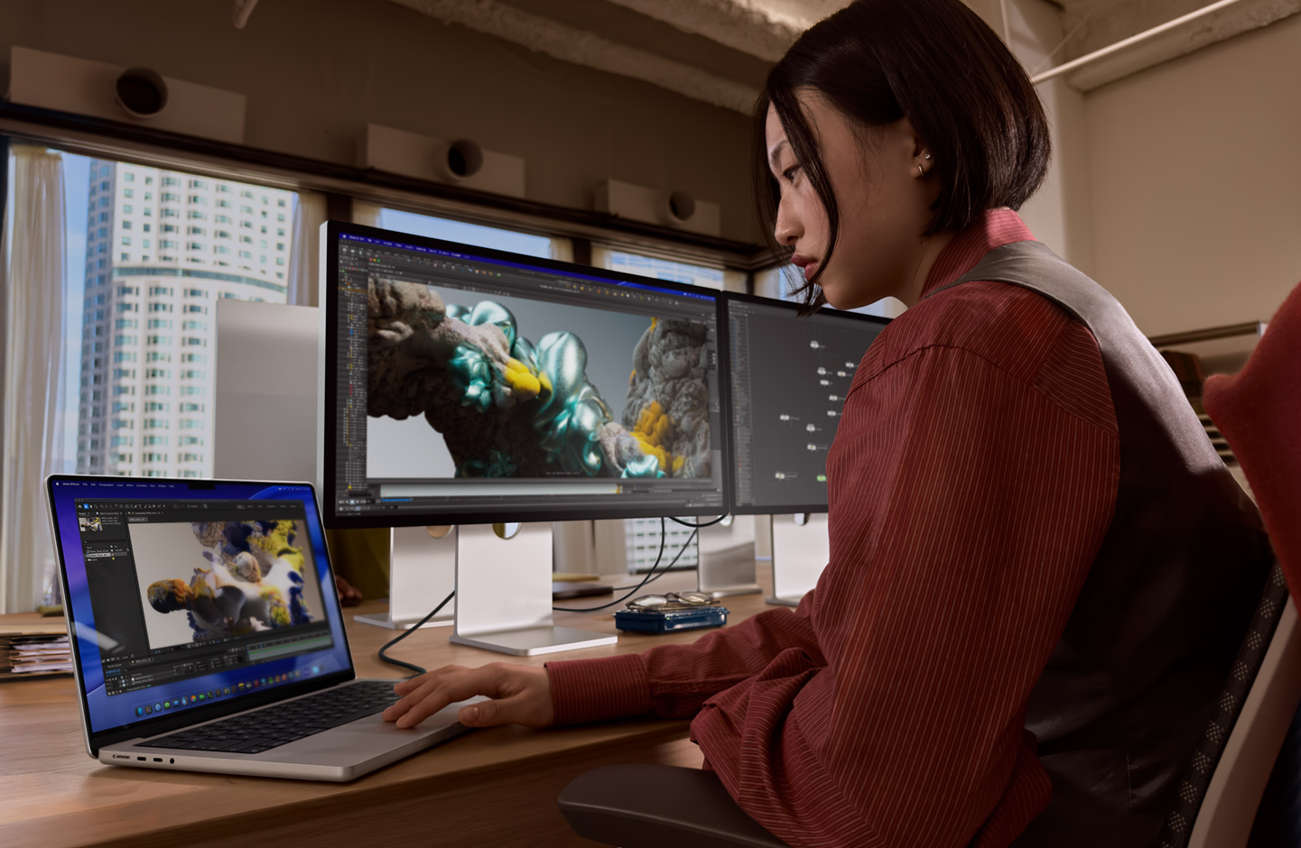 Pracująca w biurze osoba używa laptopa MacBook, który jest podłączony do monitora Studio Display XDR za pomocą portu Thunderbolt 5