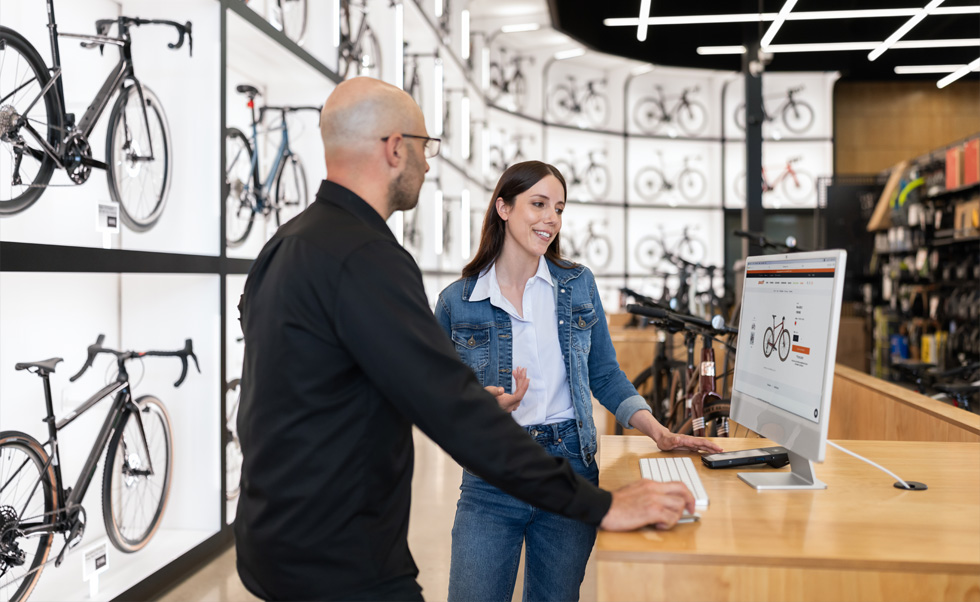 Julien Sicuro, gerente de tienda, ayuda a una clienta a escoger una bicicleta en la nítida pantalla Retina de un iMac.